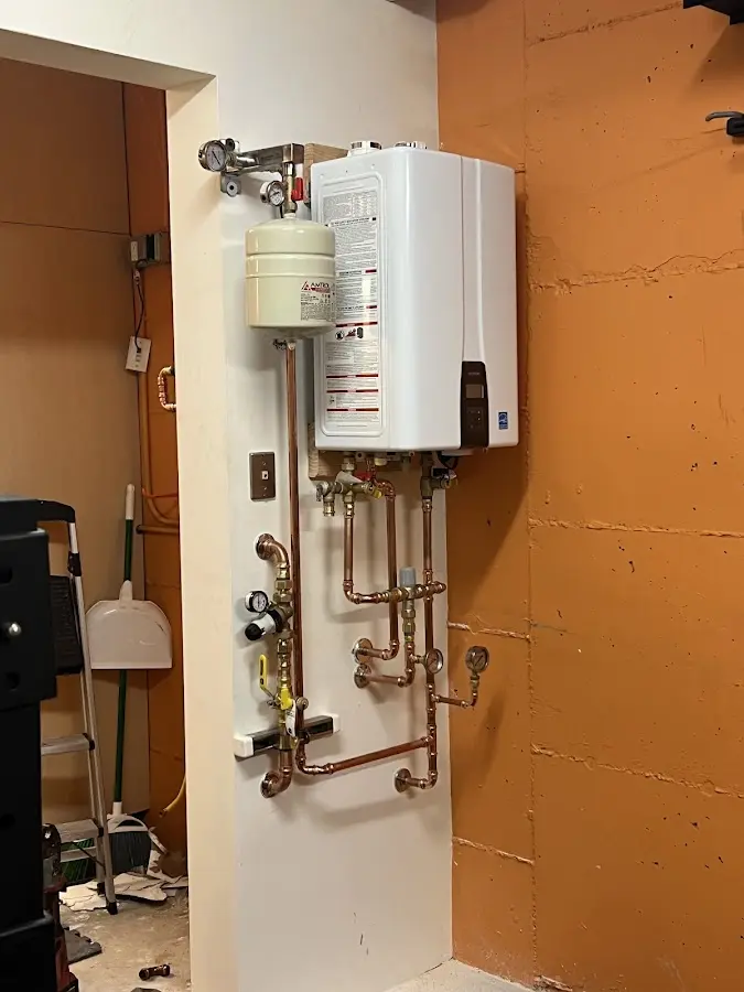Plumbing technician inspecting water heater connections in Burnham